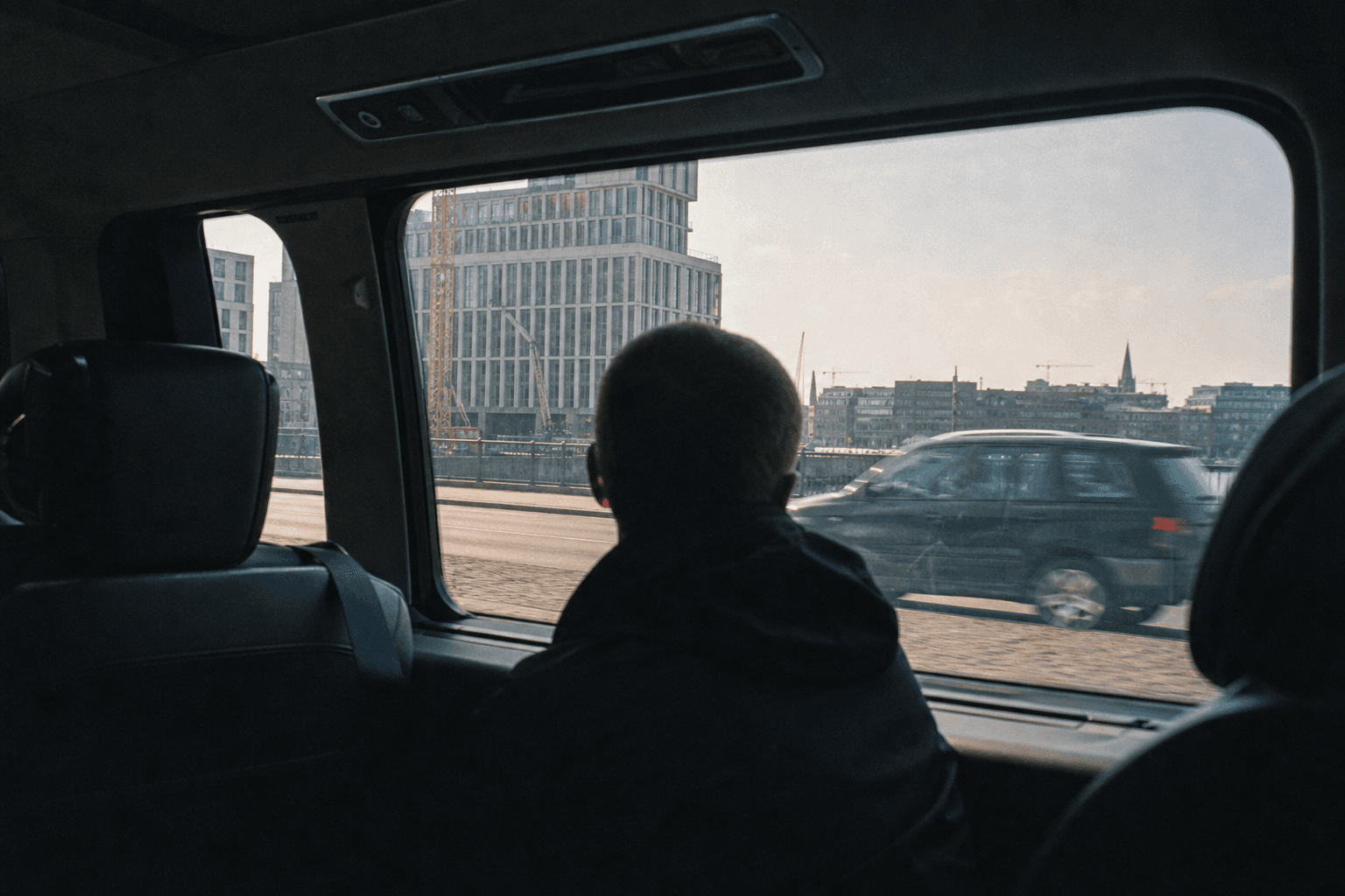 Pasajeros de espaldas mirando el paisaje urbano belga por la ventana de una furgoneta premium